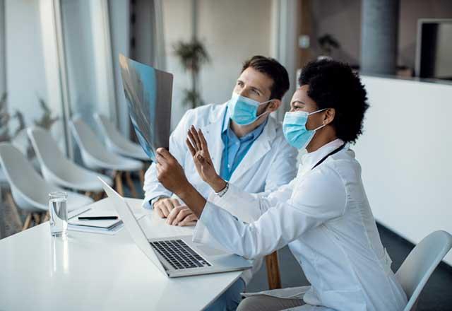 Male and female doctors with masks on looking at xrays.